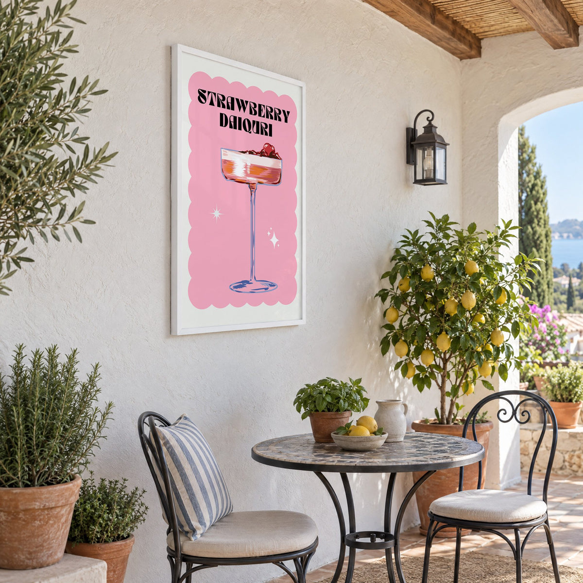 Strawberry daiquiri pink coupe print in a white frame on a sunny patio wall beside a potted lemon tree