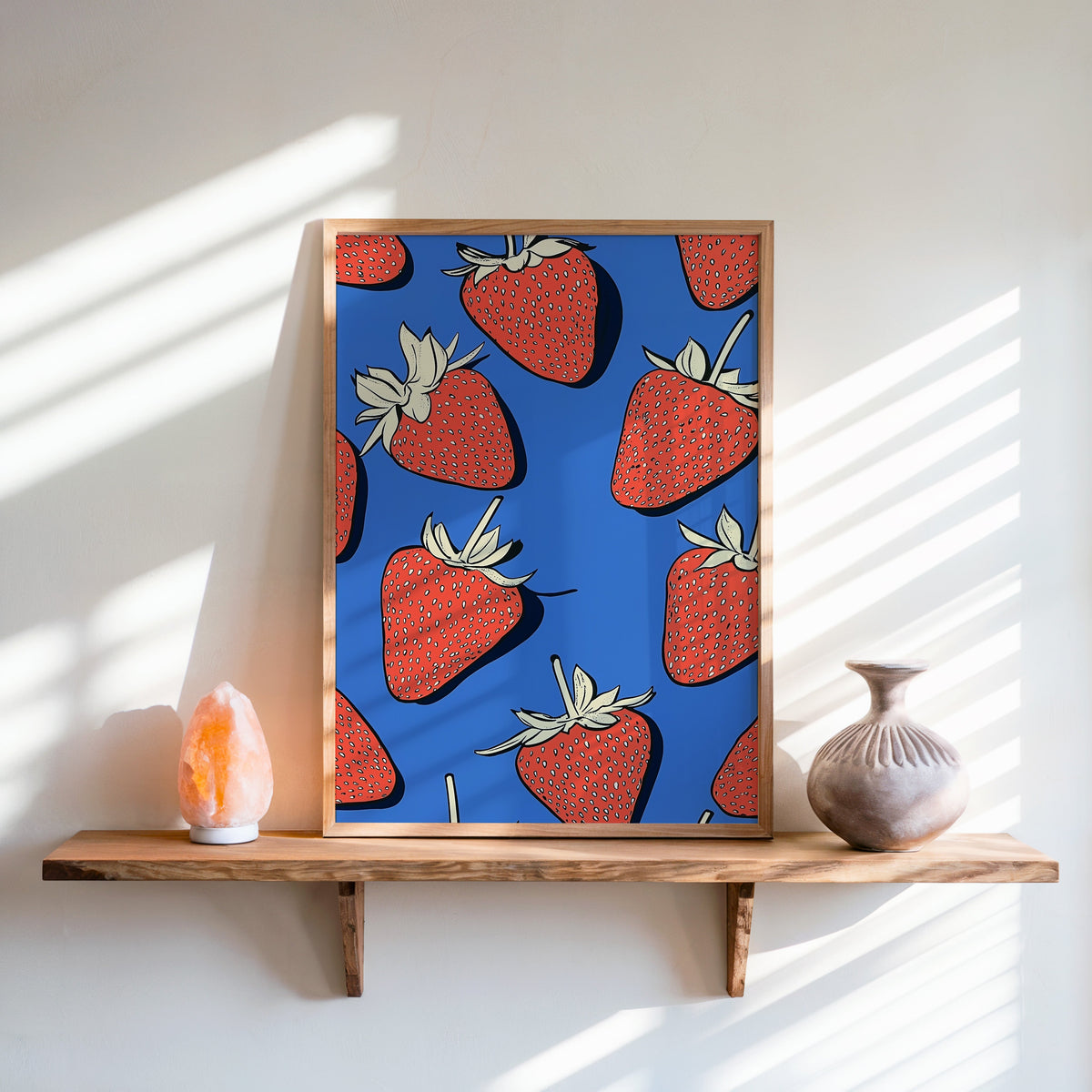 Strawberry pattern print in an oak frame on a live-edge shelf beside a salt lamp