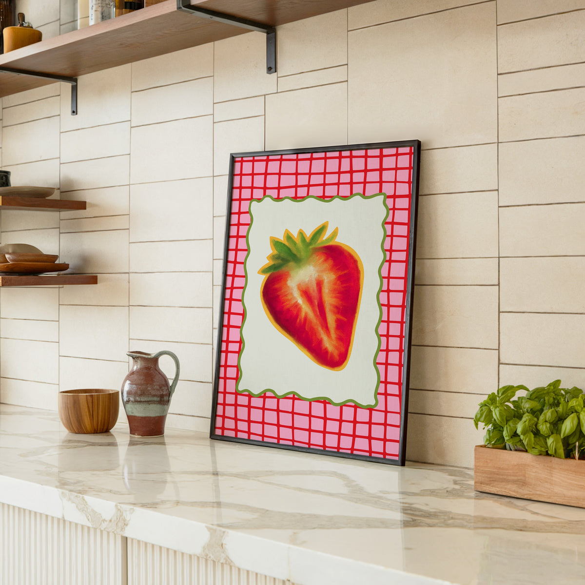 Strawberry red grid print in a black frame leaning on a marble counter in a tiled kitchen