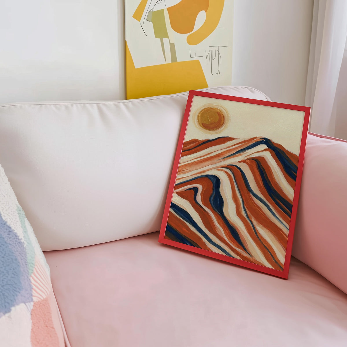Wavy striped mountain print shown in a red frame leaning on a blush pink sofa