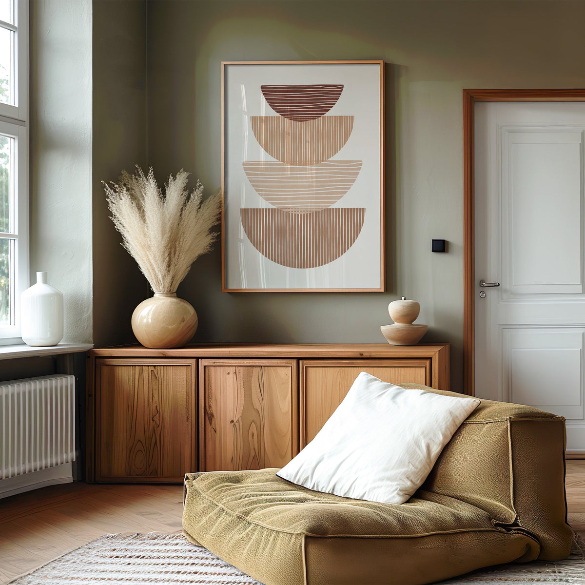 Striped stacked bowls earth tone print in an oak frame on an olive green wall above a wood sideboard with pampas