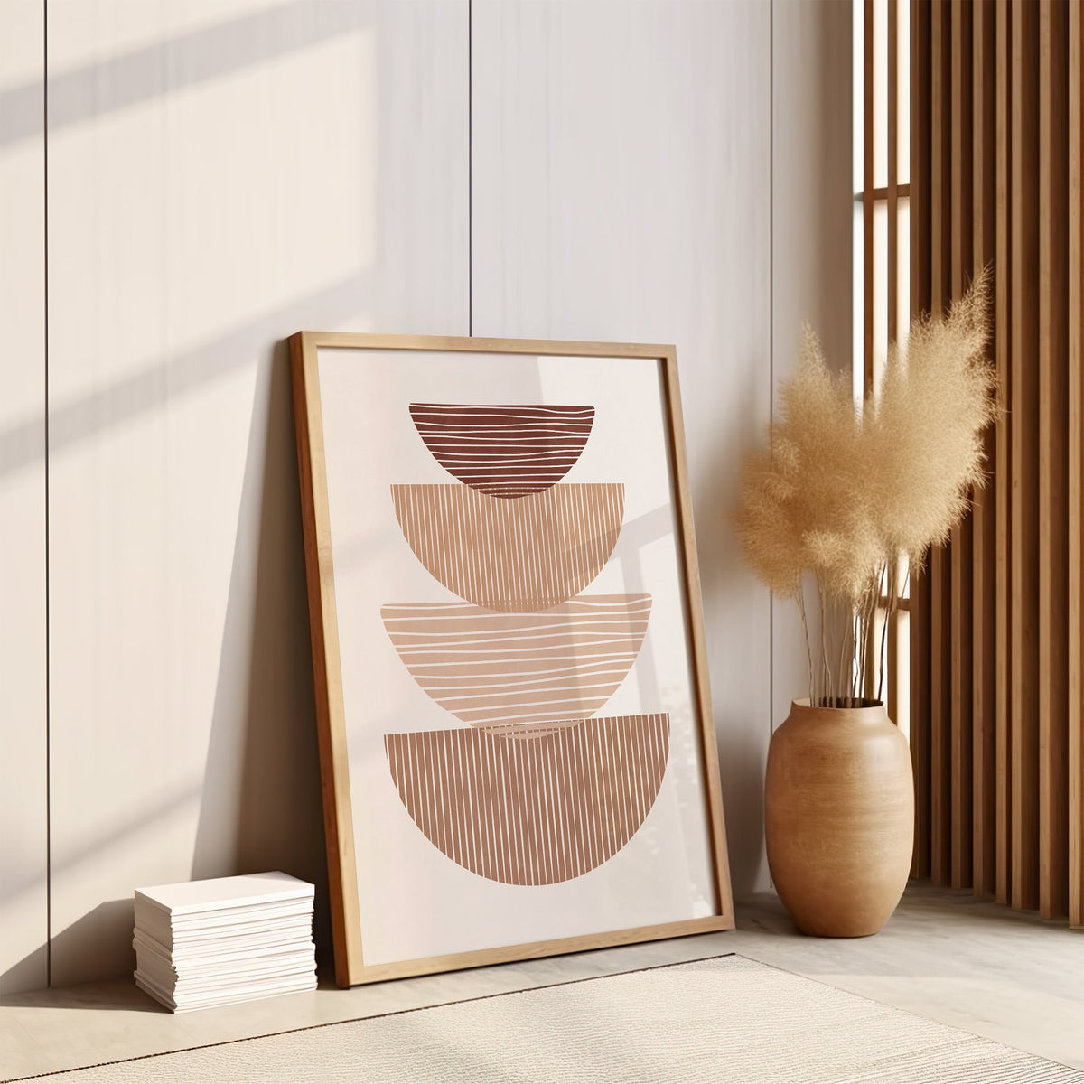 Striped stacked bowls earth tone print in an oak frame leaning on the floor by pampas grass and a wood slat screen