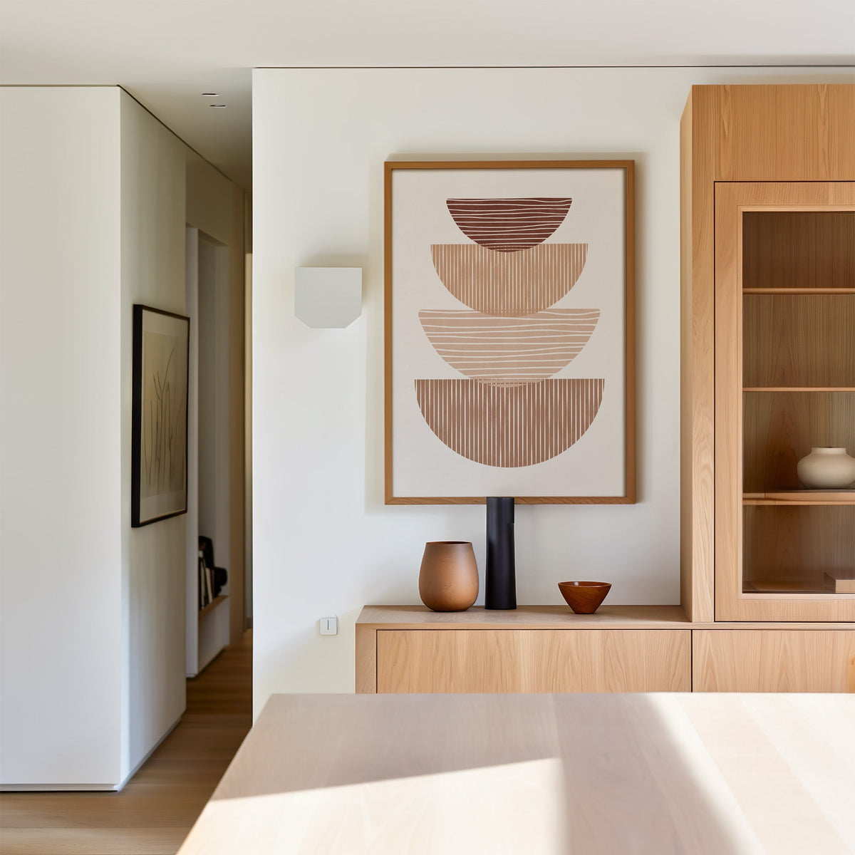 Striped stacked bowls earth tone print in an oak frame above a light oak sideboard in a dining room
