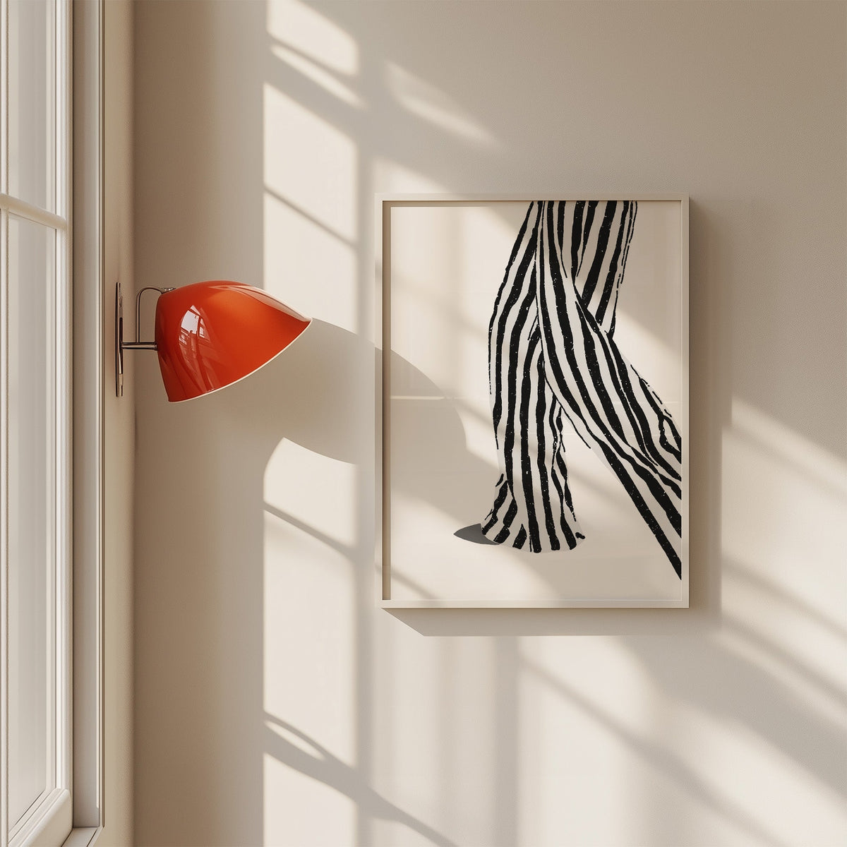 Walking legs in striped trousers graphic print in a white frame on a sunlit wall beside a red sconce