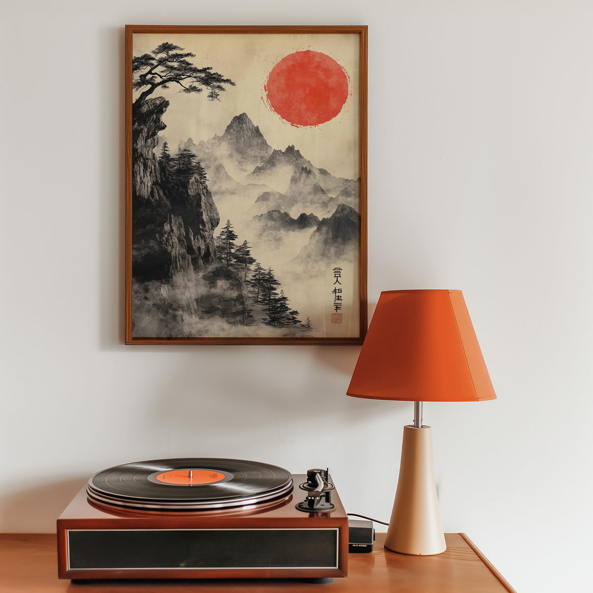 Sumi-e misty mountains and red sun print in a walnut frame above a sideboard with a record player