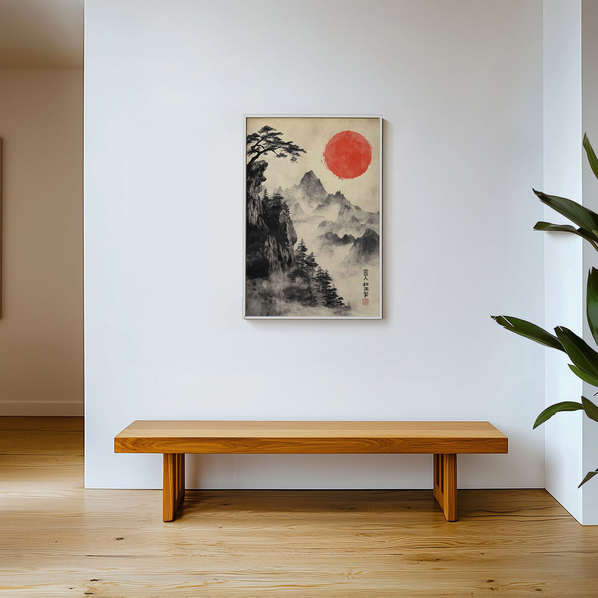 Sumi-e misty mountains and red sun print shown in a white frame above a wooden entryway bench