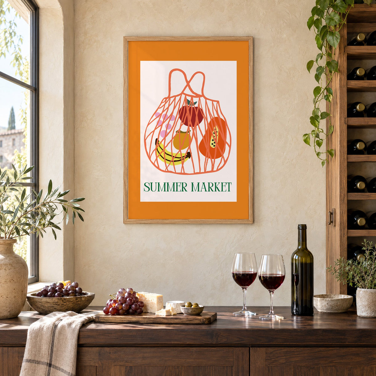 SUMMER MARKET fruit net bag print in an oak frame on a limewashed wall above a wine counter with red wine, cheese and grapes
