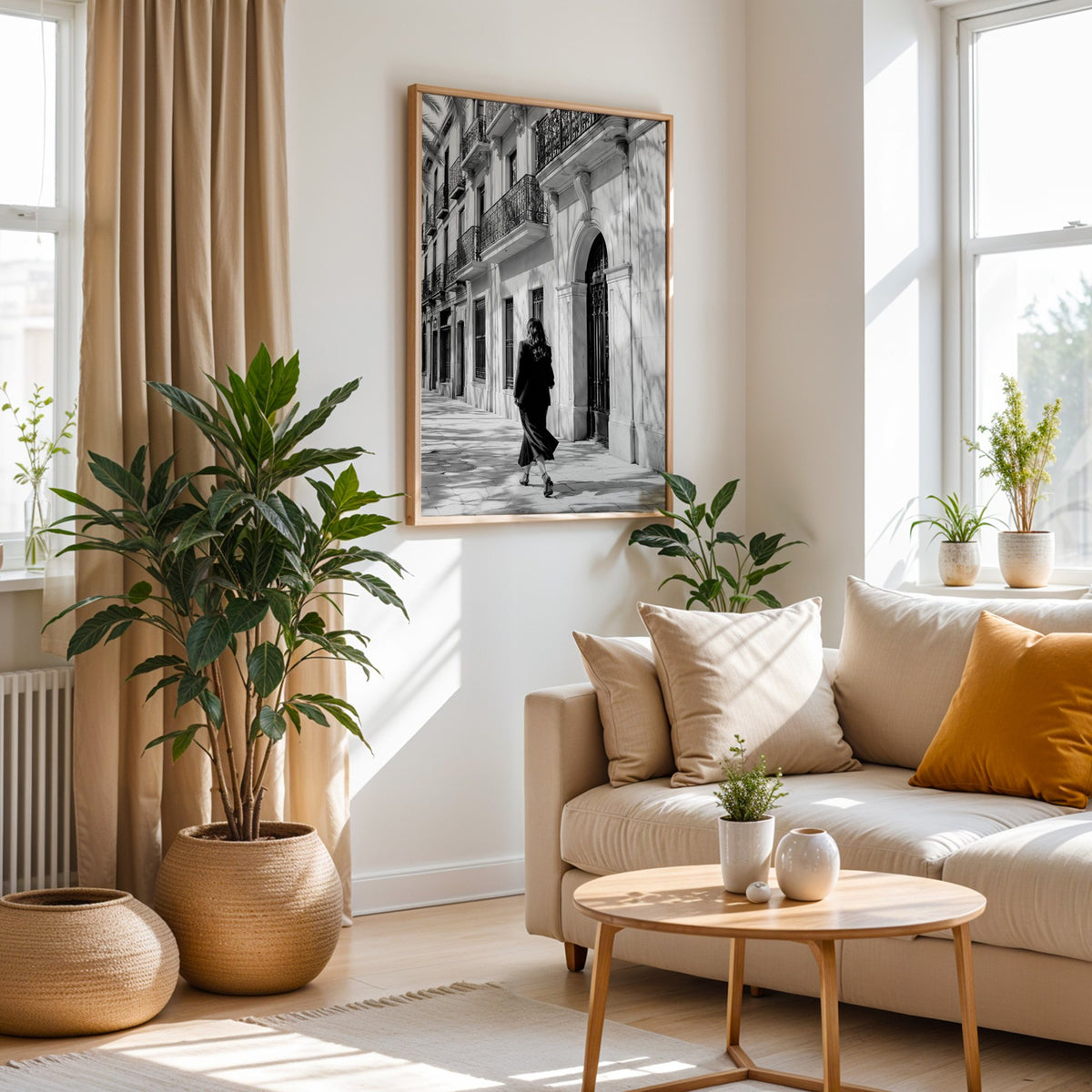 Black and white woman walking under iron balconies print in an oak frame above a cream sofa beside woven planters