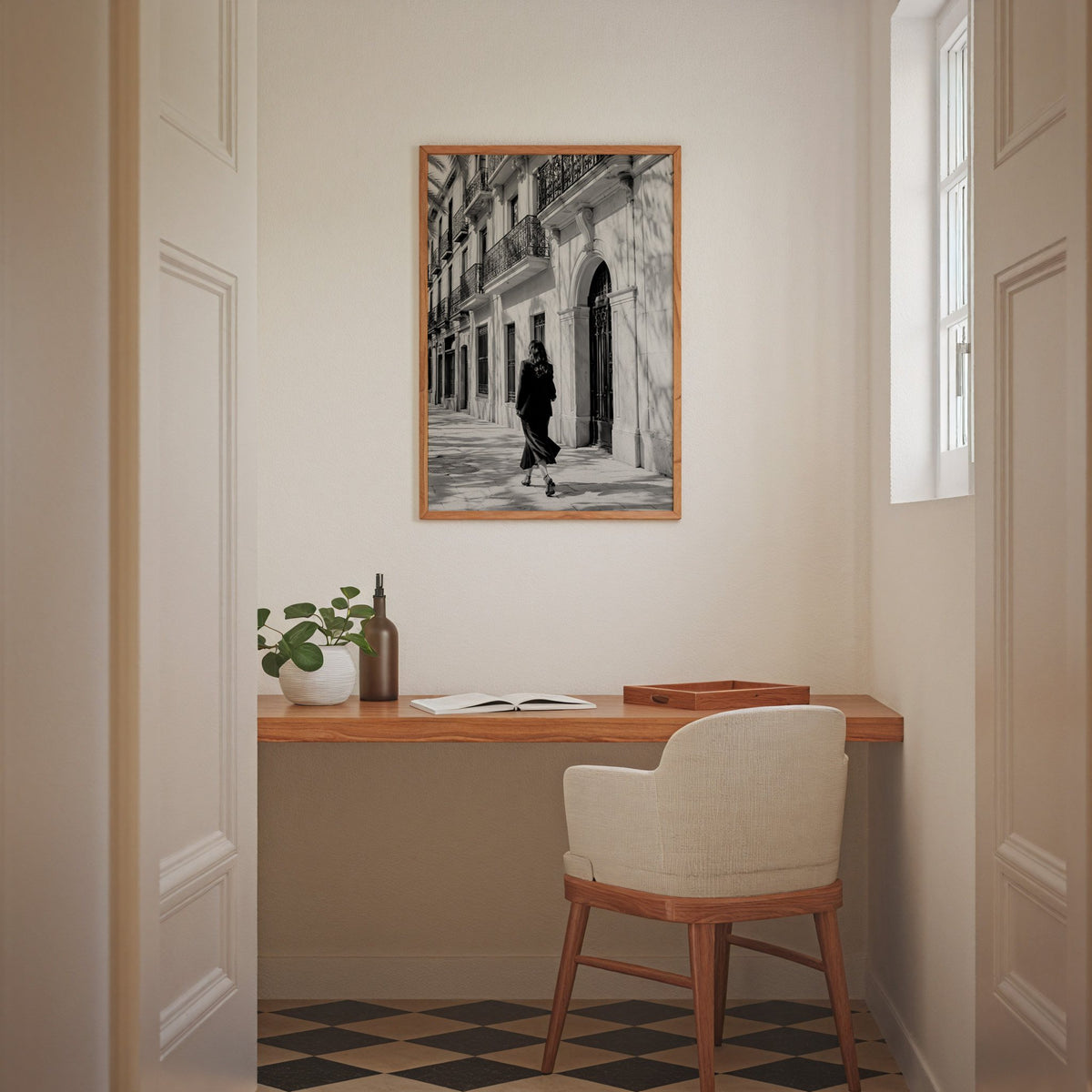 Black and white woman walking under iron balconies print in an oak frame above a home office desk nook