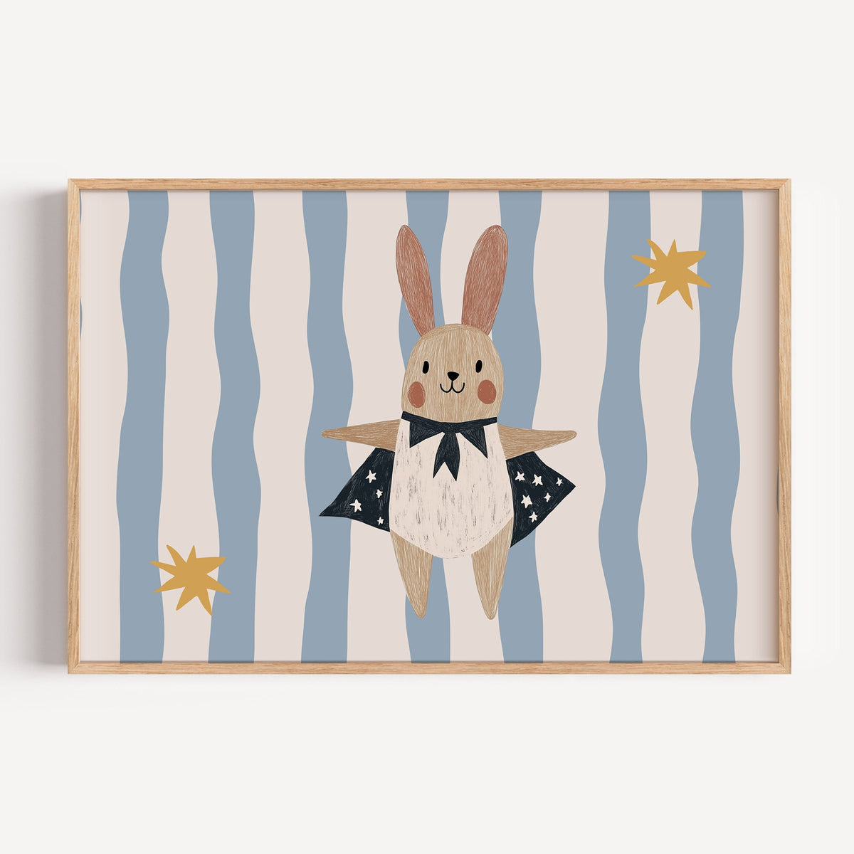 Landscape superhero bunny star cape nursery print in a light oak frame on a plain white wall