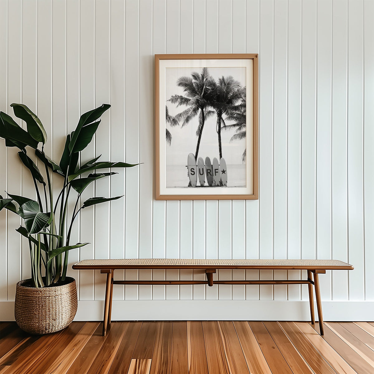 Five surfboards spelling SURF under coconut palms print in a wood frame with a white mat above a cane bench