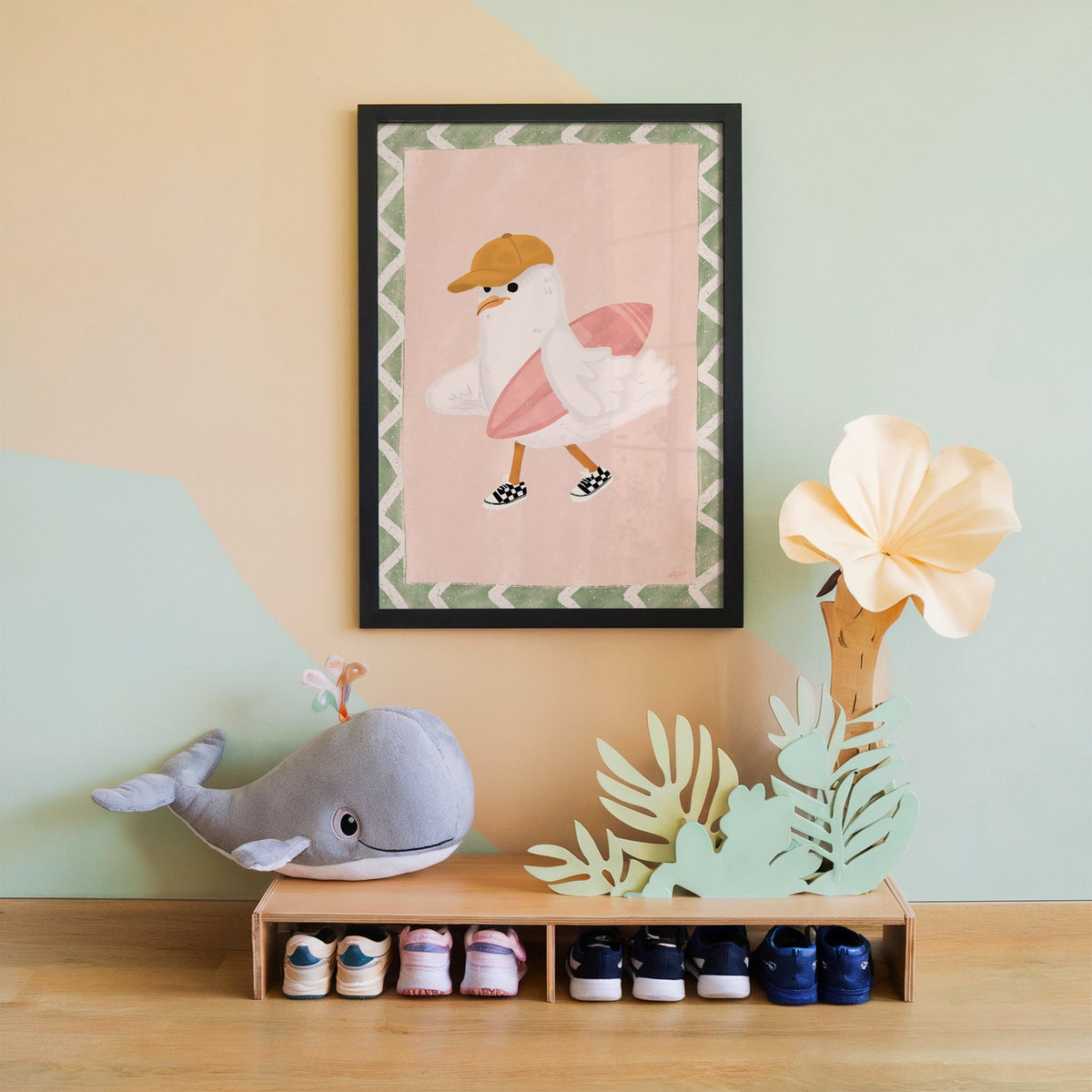 Surfer seagull with pink surfboard nursery print in a black frame on a mint and peach wall above a whale plush