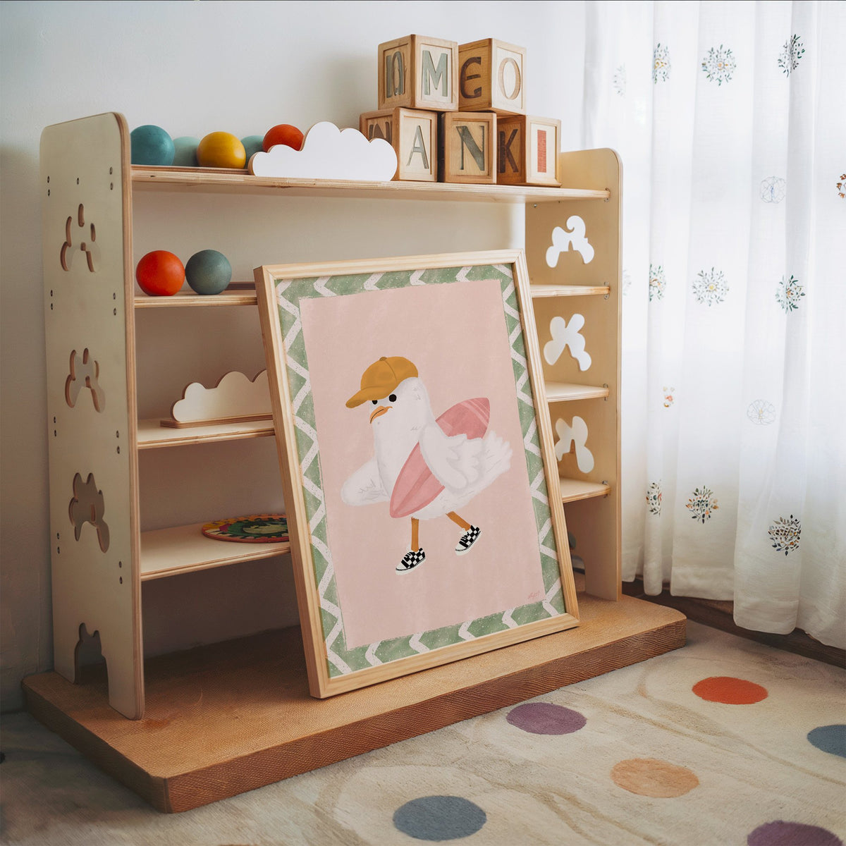 Surfer seagull with pink surfboard nursery print in an oak frame leaning on a toy shelf with wooden letter blocks