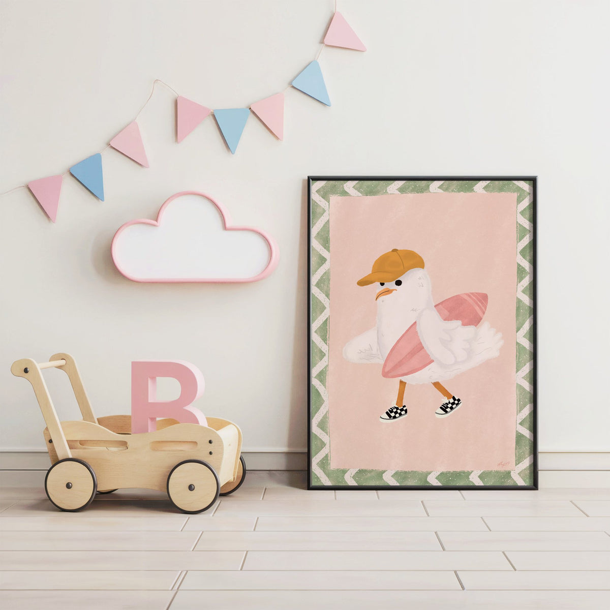 Surfer seagull with pink surfboard nursery print in a black frame under pastel bunting by a wooden baby walker