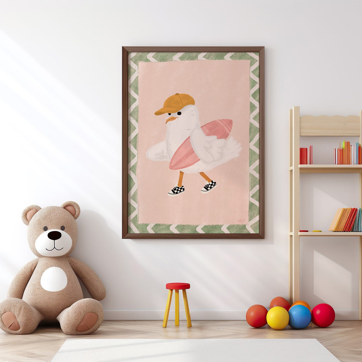 Surfer seagull with pink surfboard nursery print in a walnut frame above a big teddy bear by a bookshelf