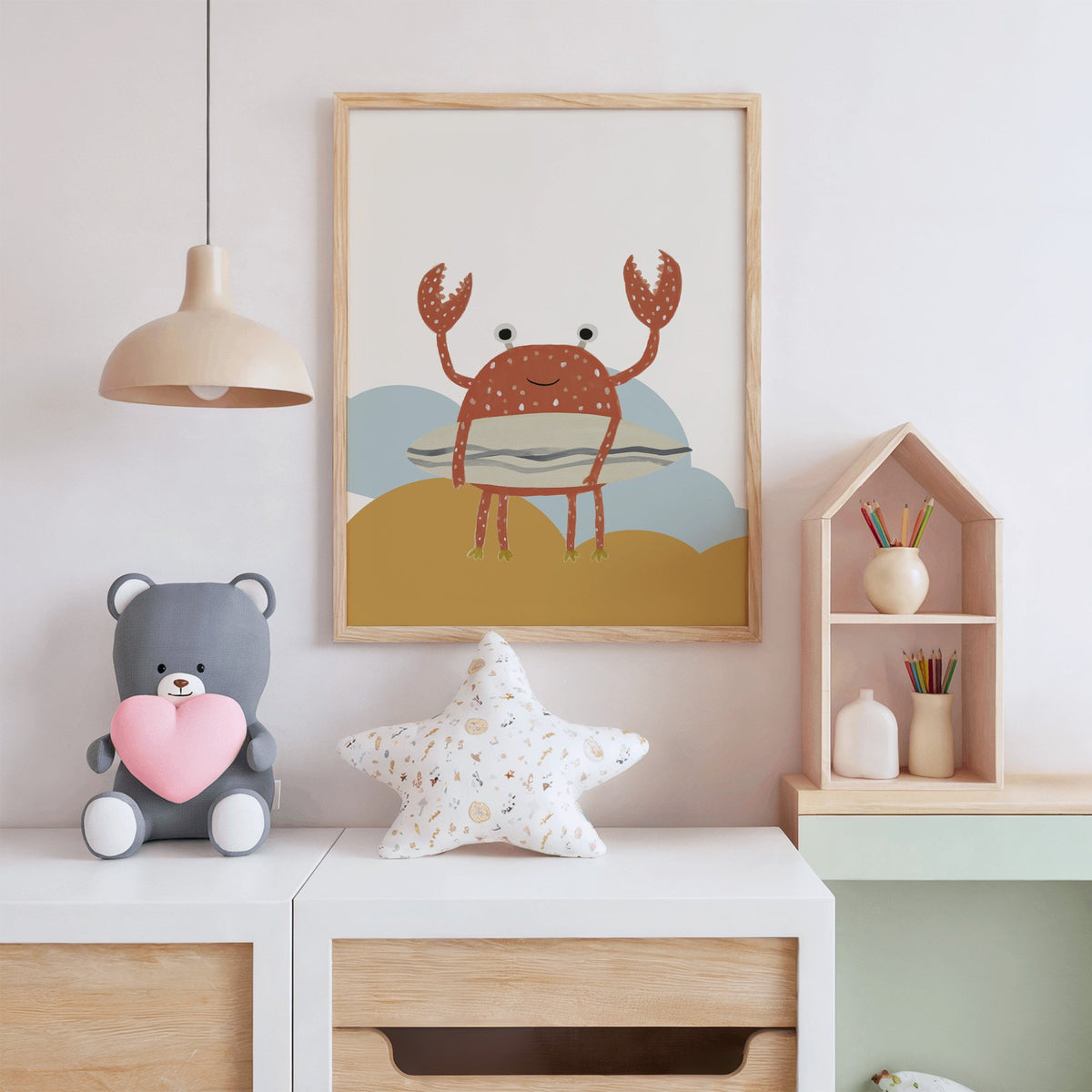 Surfing crab mustard hills nursery print in an oak frame above a white dresser with a star pillow and house shelf