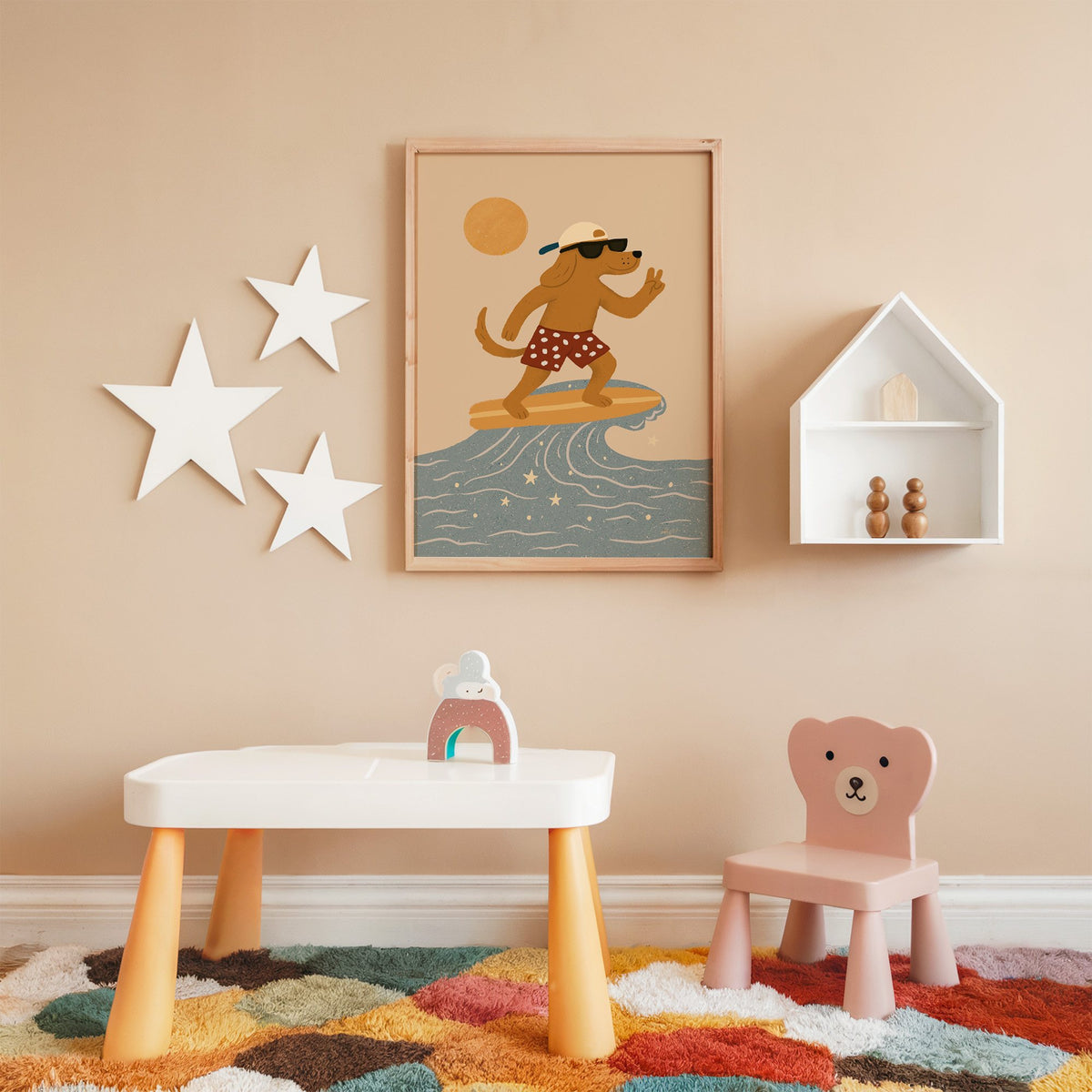 Surfing dog with peace sign nursery print in an oak frame on a peach wall above a kids table with wall stars