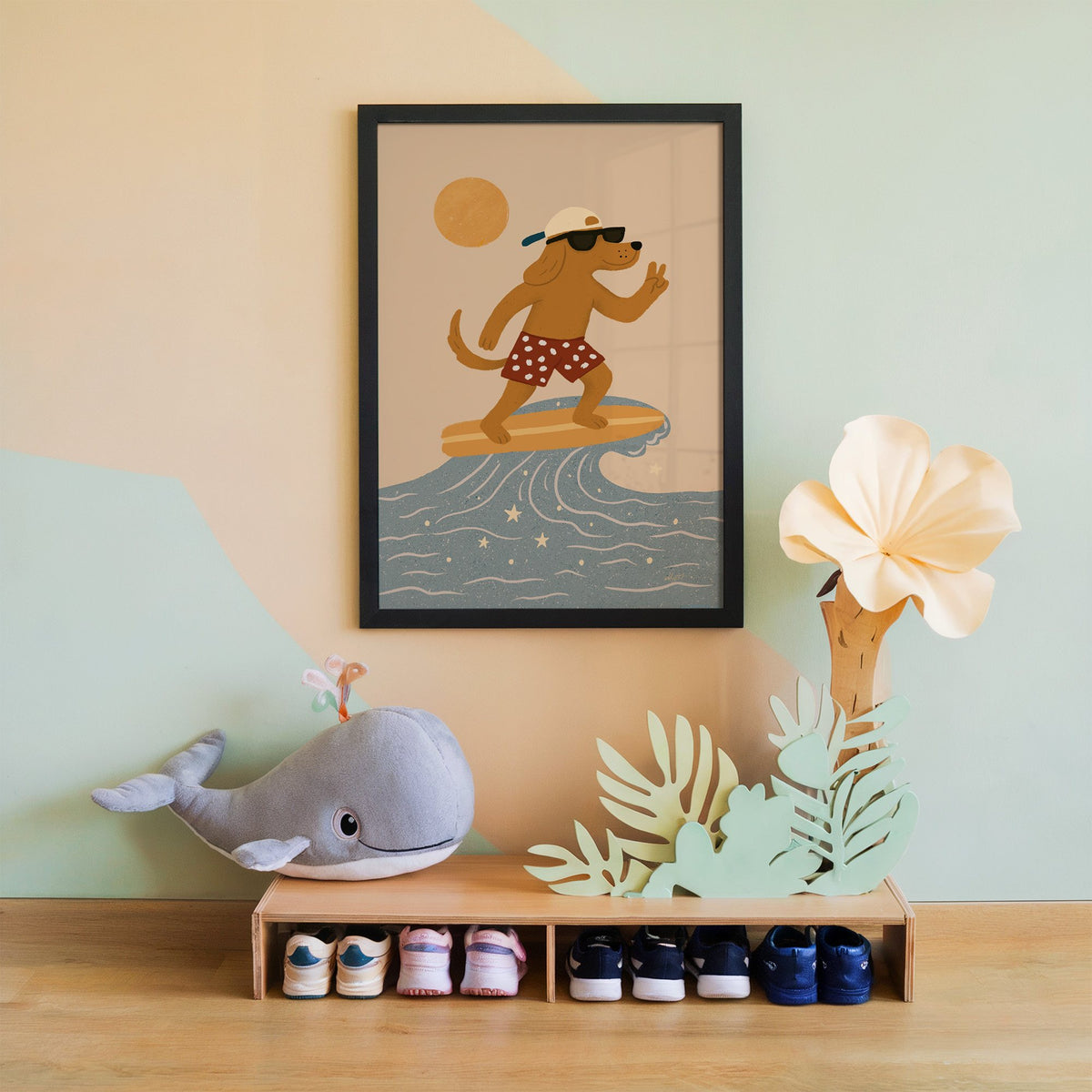 Surfing dog with peace sign nursery print in a black frame on a mint and peach wall above a whale plush