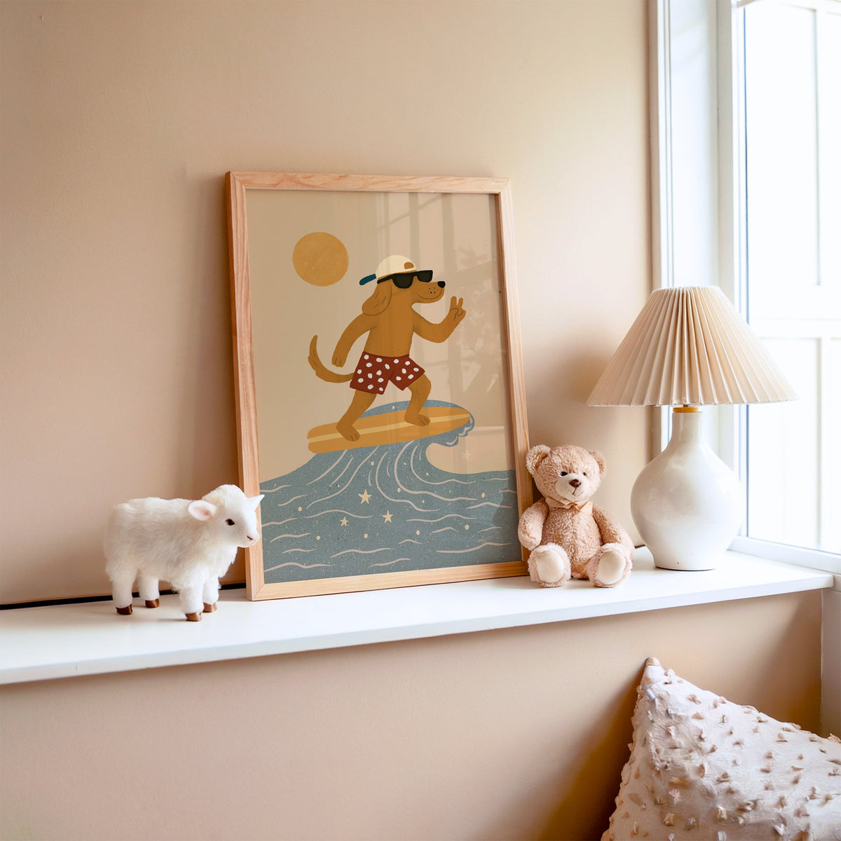 Surfing dog with peace sign nursery print in an oak frame on a window ledge with a toy lamb and teddy