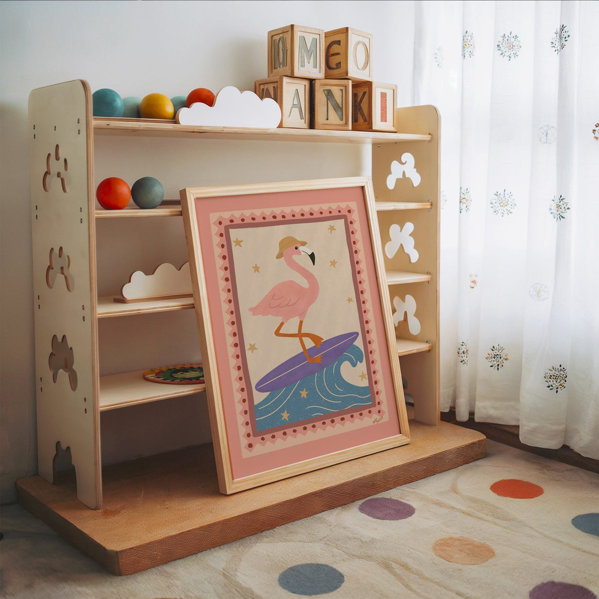 Flamingo on purple surfboard nursery print in an oak frame leaning on a toy shelf with wooden letter blocks