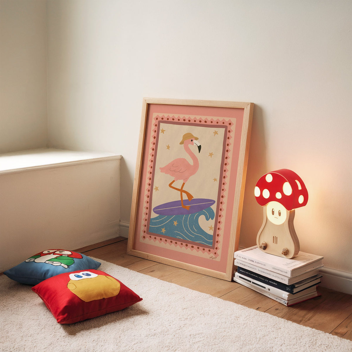 Flamingo on purple surfboard nursery print in an oak frame leaning on a rug beside a mushroom lamp and floor cushions