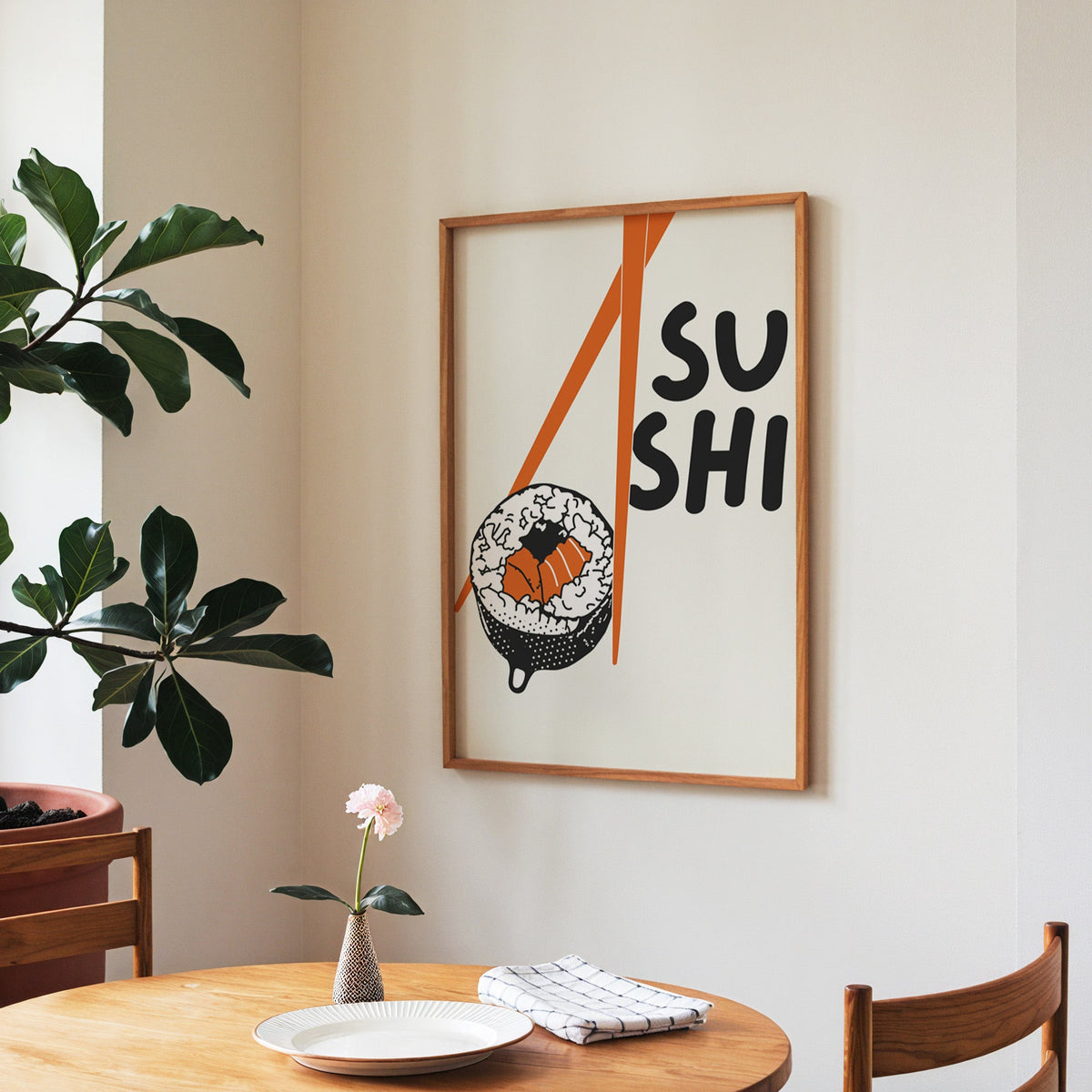 Sushi roll print in a walnut frame above a round table beside a fiddle-leaf fig