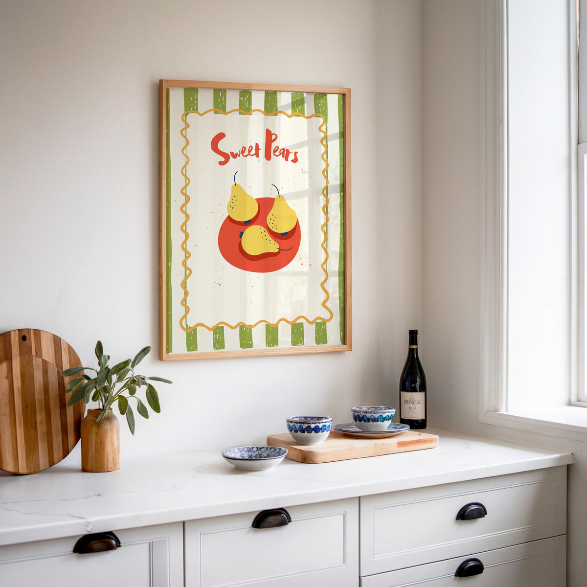 Sweet Pears print in an oak frame above a white sideboard with a bottle of wine