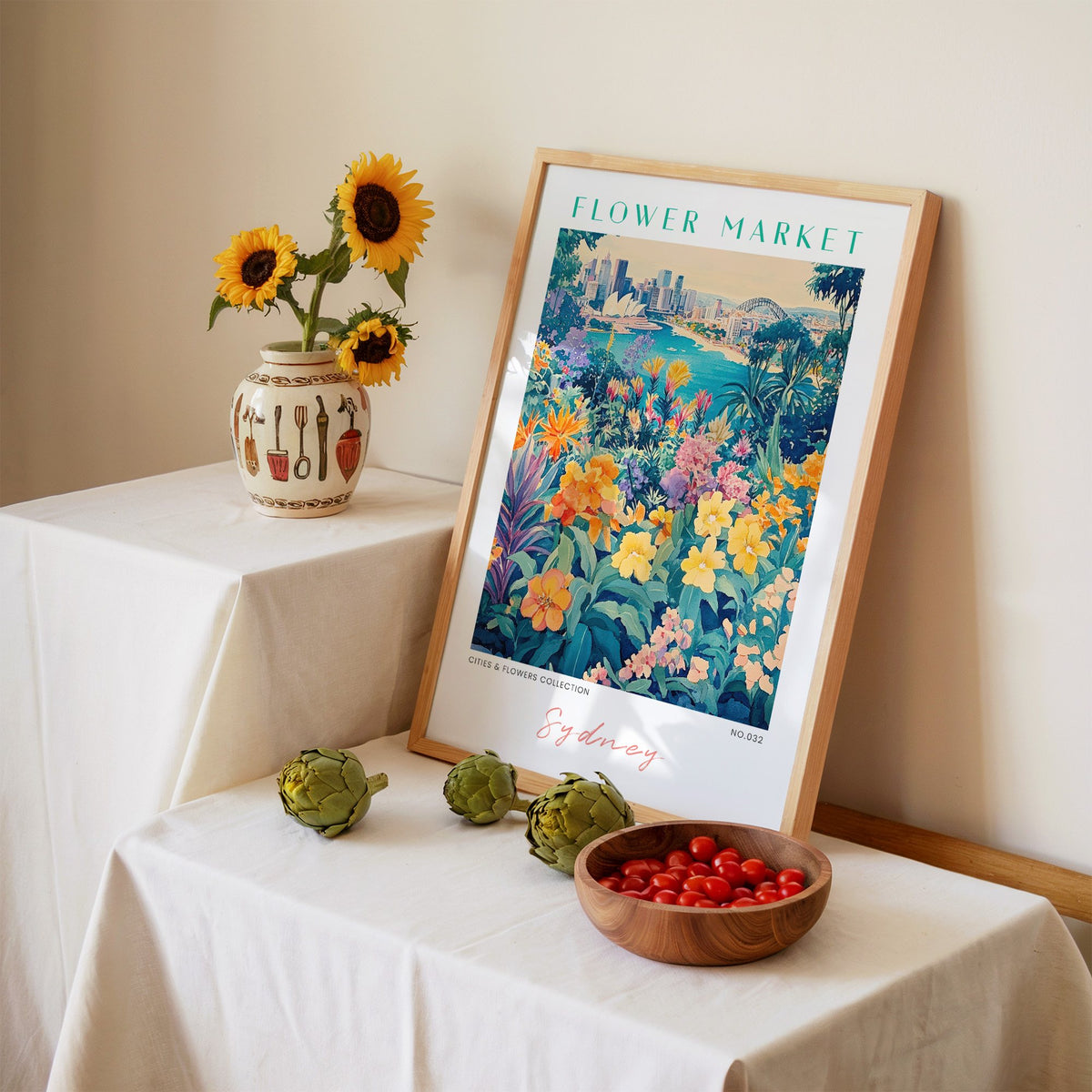 Sydney flower market print in an oak frame leaning on a linen-draped table beside a vase of sunflowers