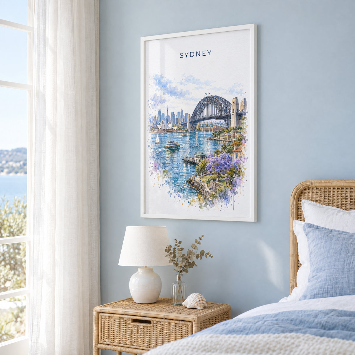Sydney Harbour Bridge watercolor print in a white frame on a pale blue wall beside a rattan bed in a coastal bedroom