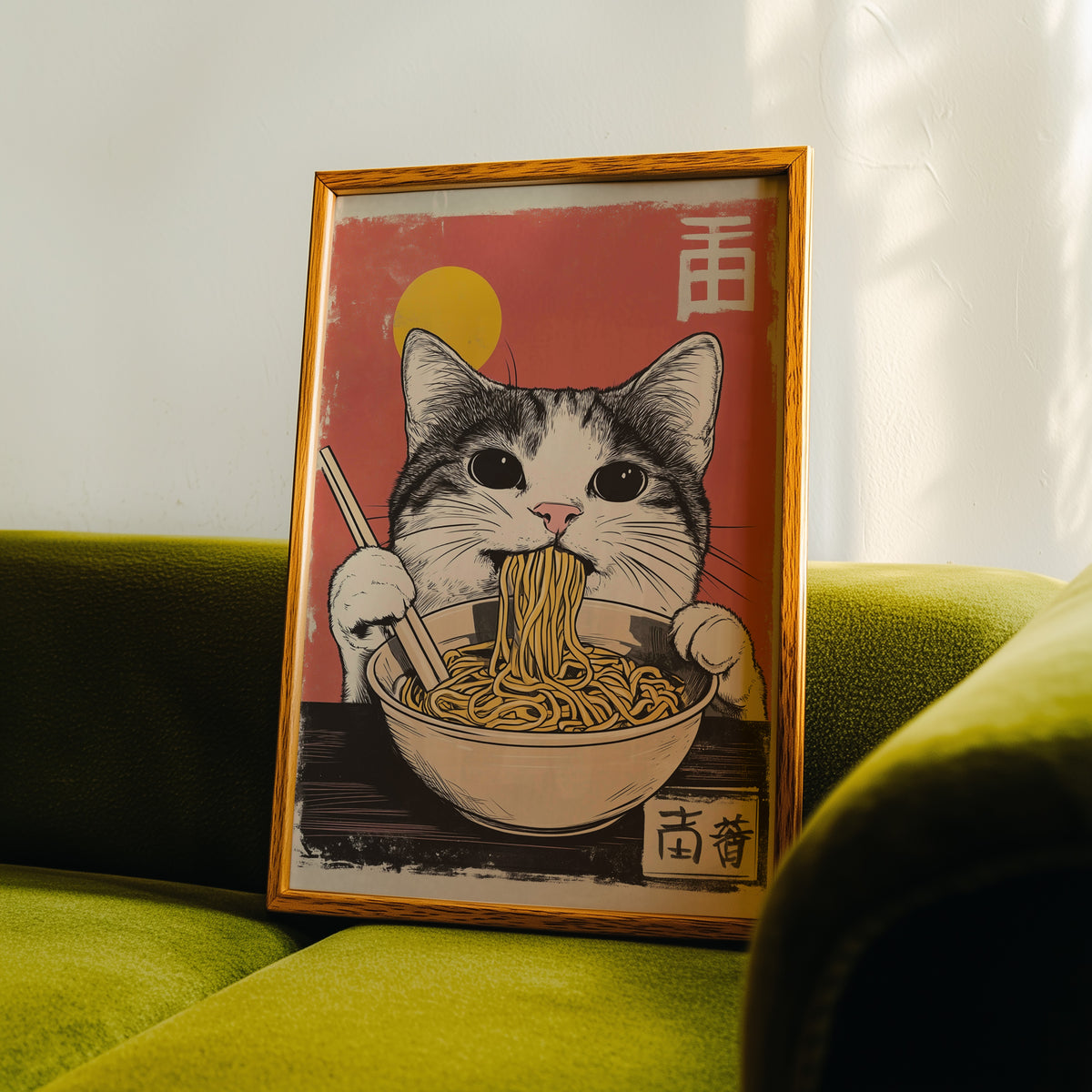 Gray tabby cat eating ramen print in an oak frame propped on a green velvet sofa