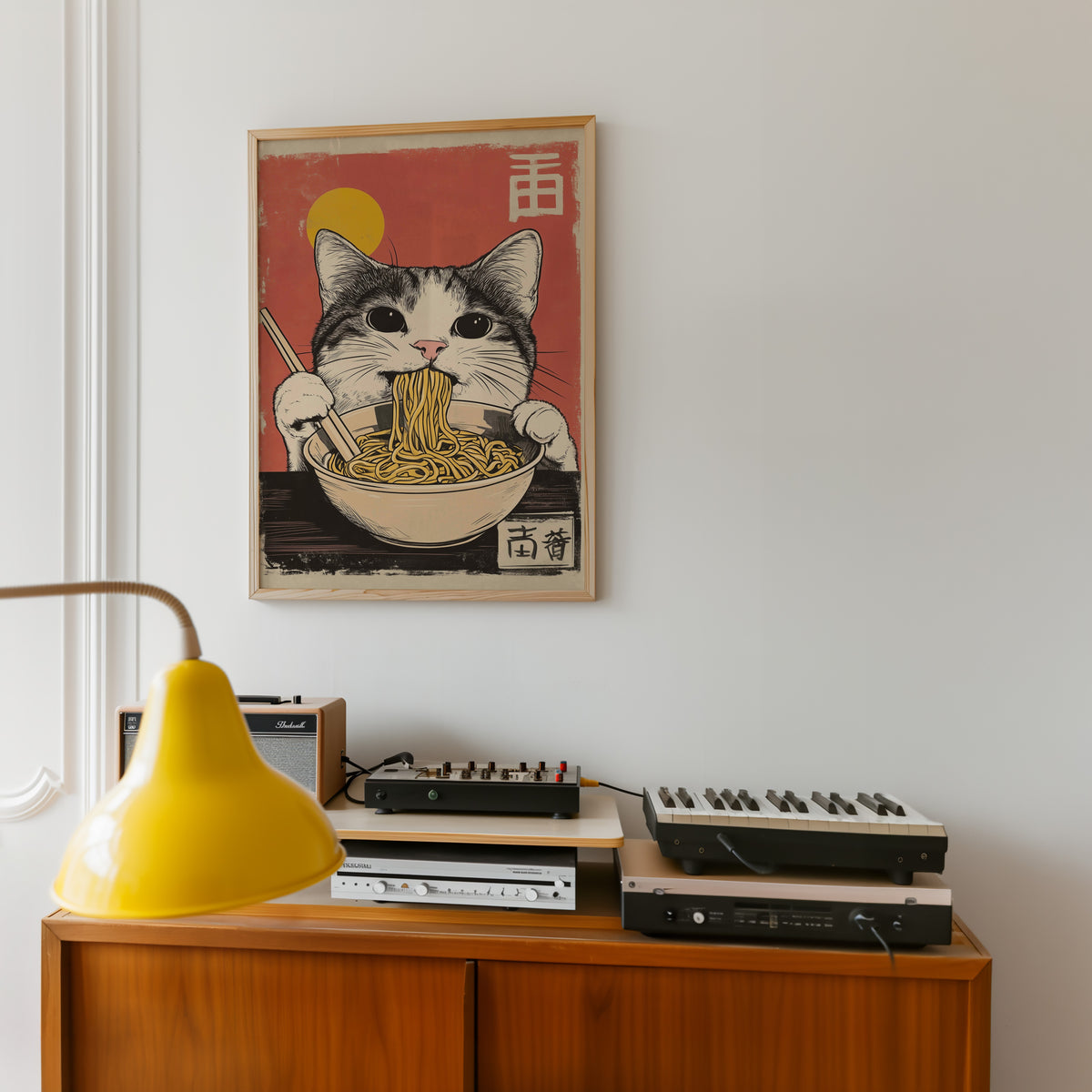 Gray tabby cat eating ramen print in an oak frame above a teak sideboard with vintage hi-fi