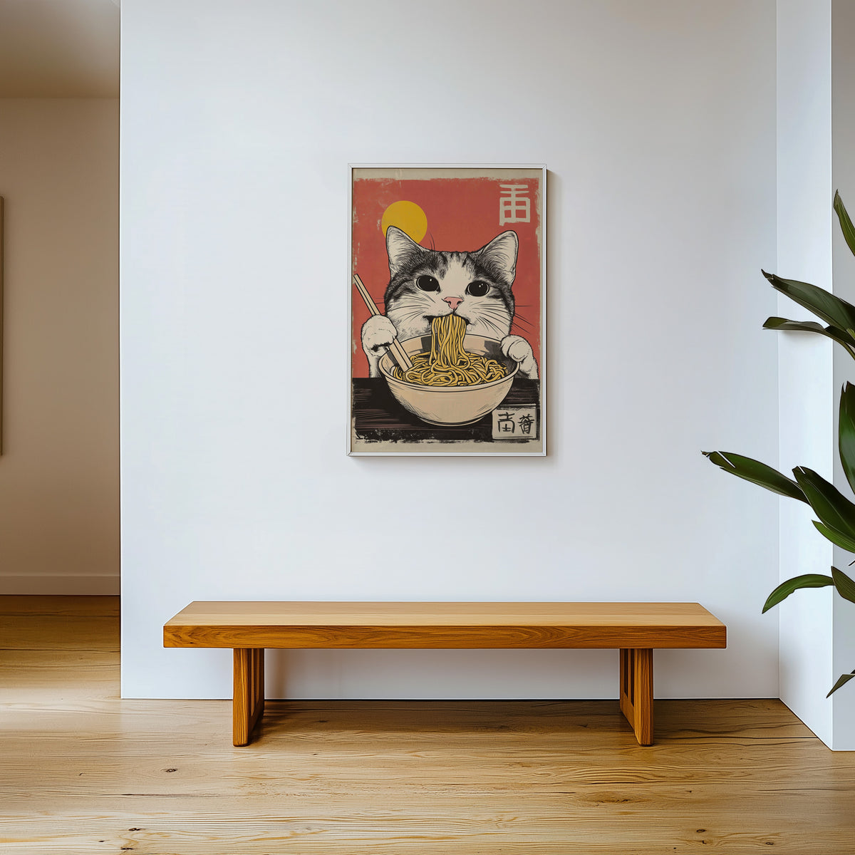 Gray tabby cat eating ramen print shown in a white frame above a wooden entryway bench