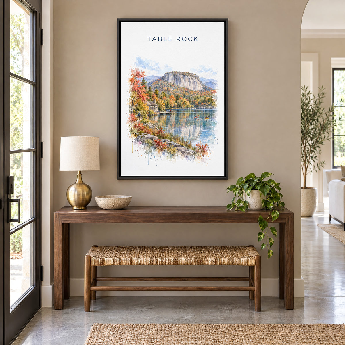 Table Rock State Park watercolor print as a black floater canvas above a walnut console and woven bench in an entryway