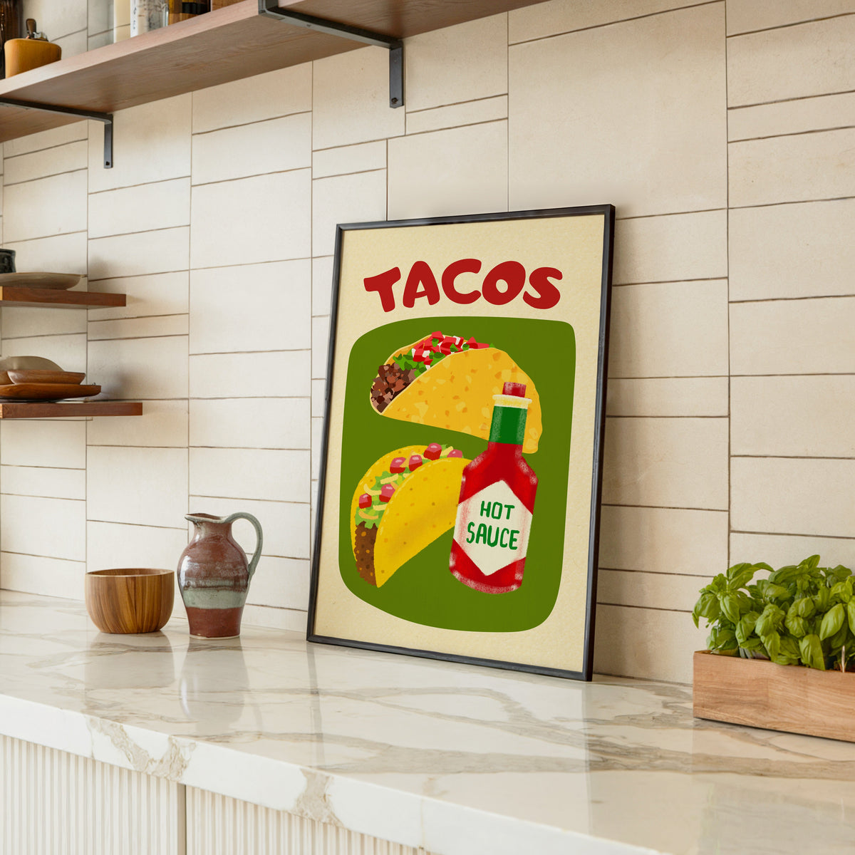 Tacos and hot sauce print in a black frame leaning on a marble counter in a tiled kitchen