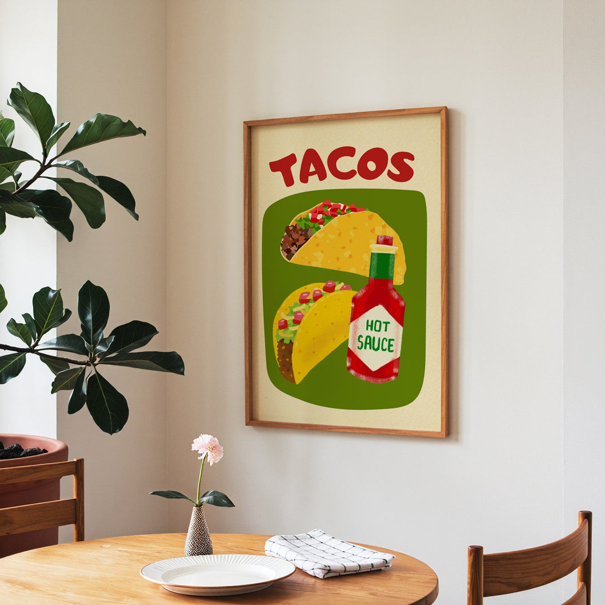 Tacos and hot sauce print in a walnut frame above a round table beside a fiddle-leaf fig