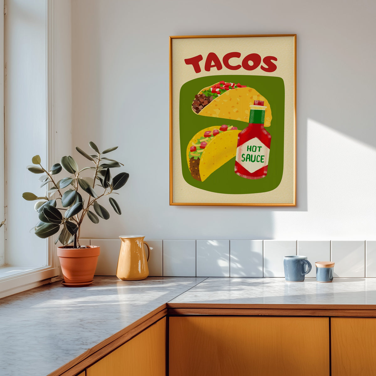 Tacos and hot sauce print shown in a gold frame above a marble counter in a tan kitchen