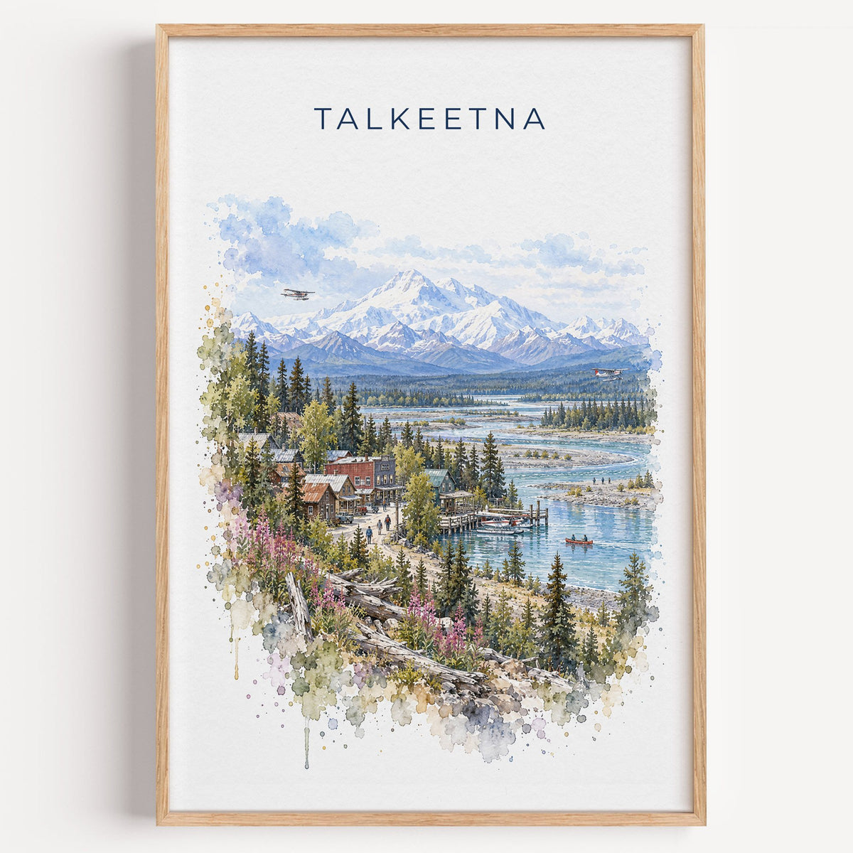 Talkeetna, Alaska watercolor print in a light oak frame on a plain white wall
