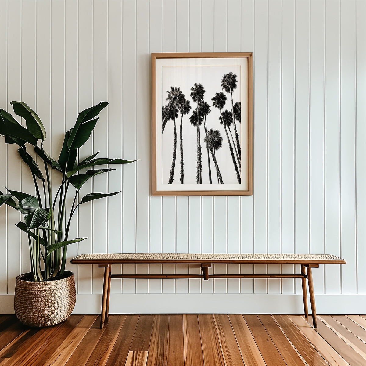 Dense fan palm grove seen from below print in a wood frame with a white mat above a cane bench