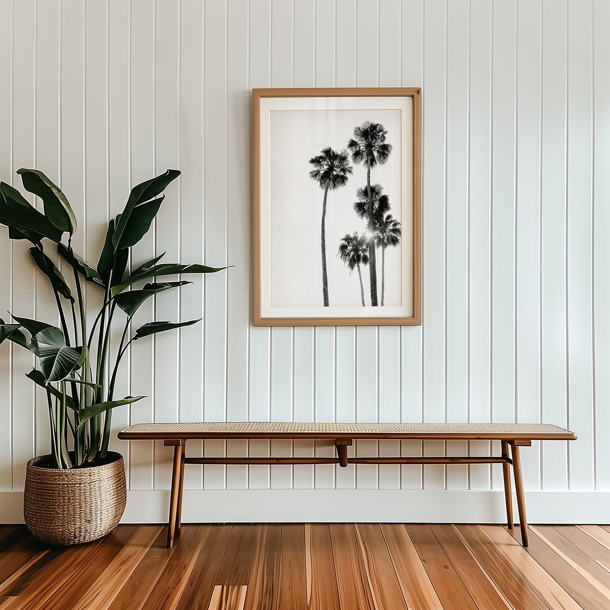 Five tall fan palms with sun flare print in a wood frame with a white mat above a cane bench
