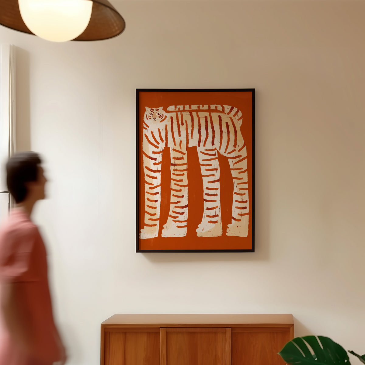 Long-legged tiger print in a black frame in a hallway under a rattan pendant
