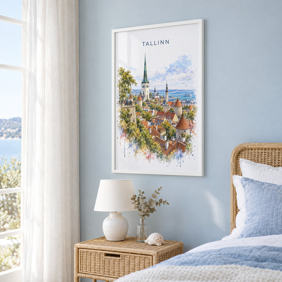 Tallinn watercolor print in a white frame on a pale blue wall beside a rattan bed in a coastal bedroom