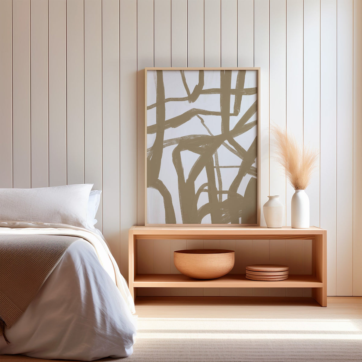 Tan crisscross brushstroke lattice print in a light oak frame on a wood bench by a bed with pampas grass