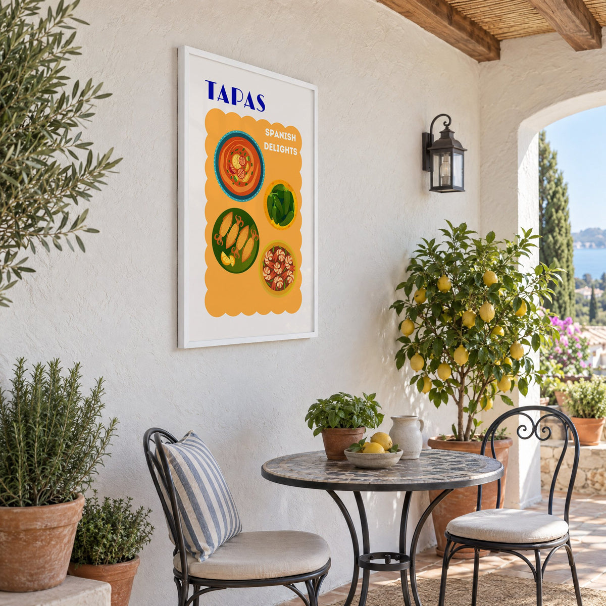 TAPAS Spanish Delights four plates print in a white frame on a sunny patio wall beside a potted lemon tree