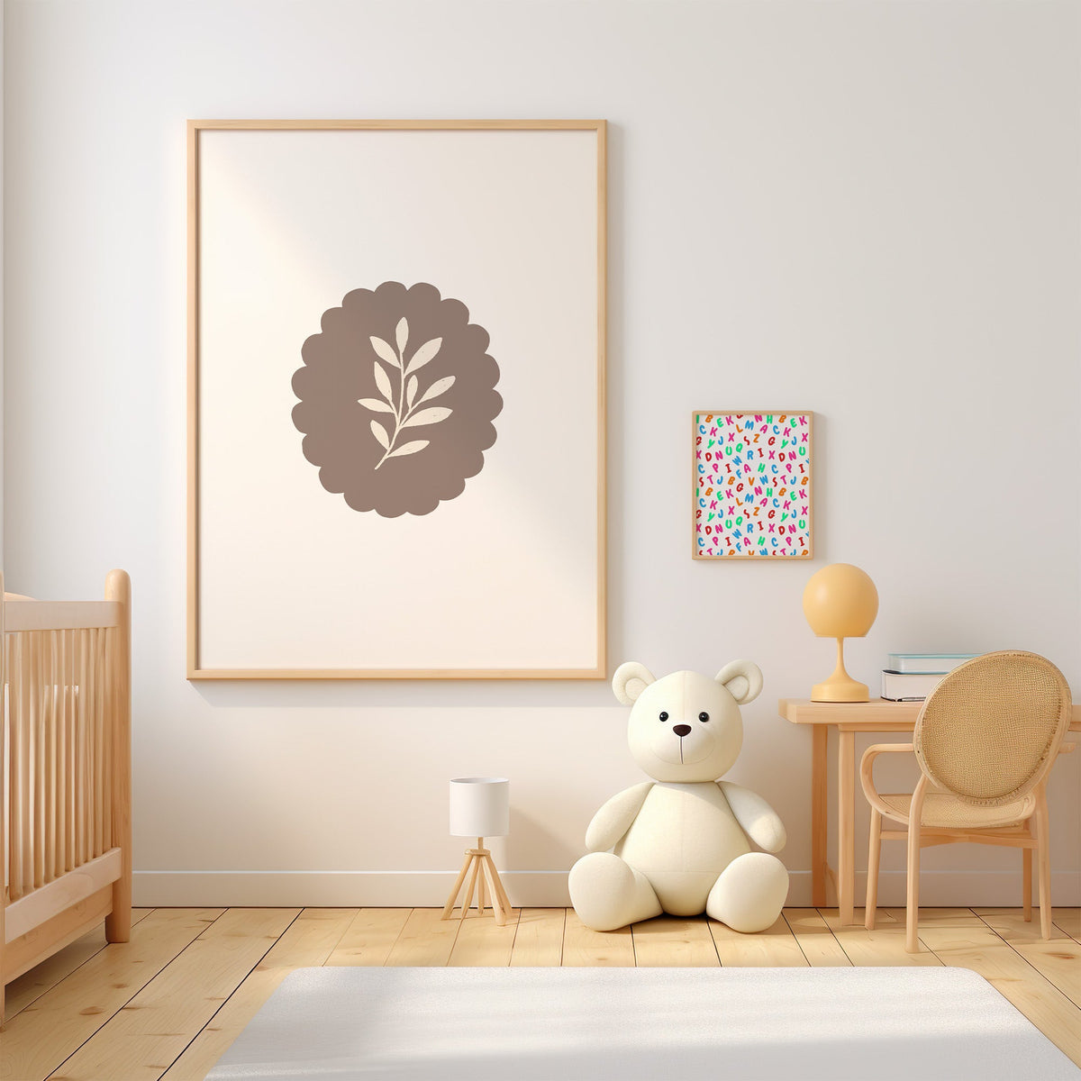 Cream leaf sprig on taupe scalloped oval nursery print in an oak frame above a wooden crib beside a cream teddy bear