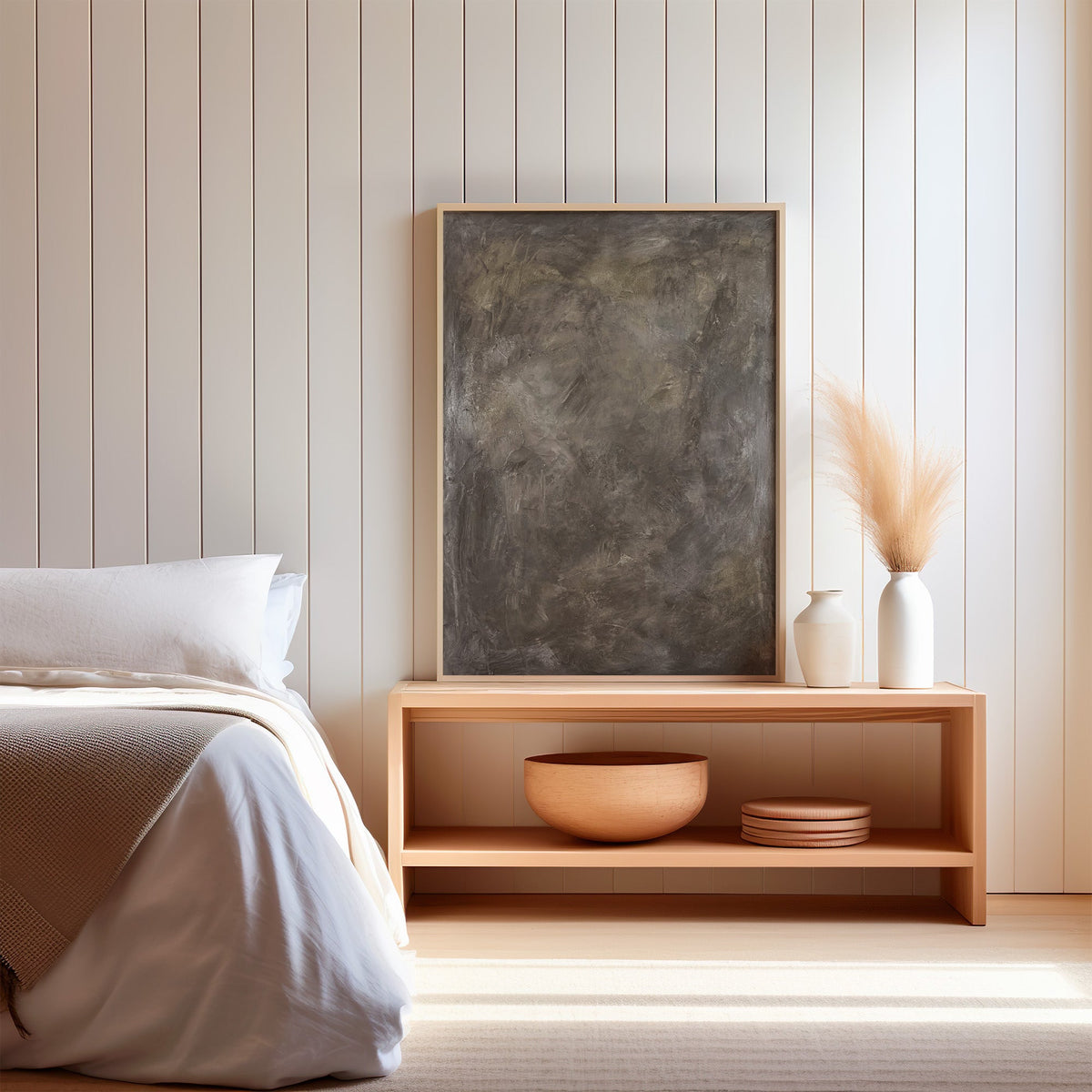 Taupe Venetian plaster textured abstract print in a light oak frame on a wood bench by a bed with pampas grass