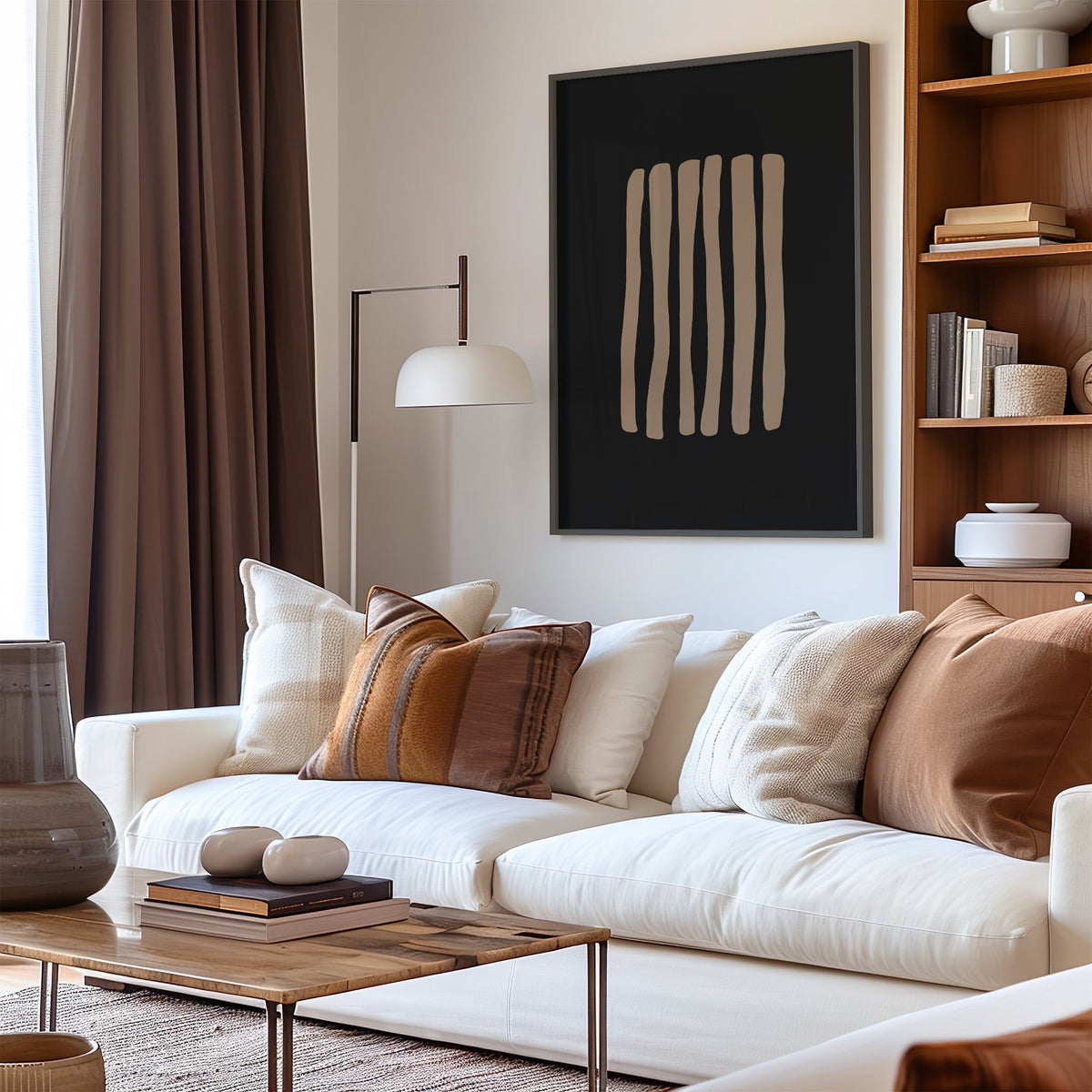 Taupe stripes on black background boho print in a black frame above a cream sofa with brown striped pillows