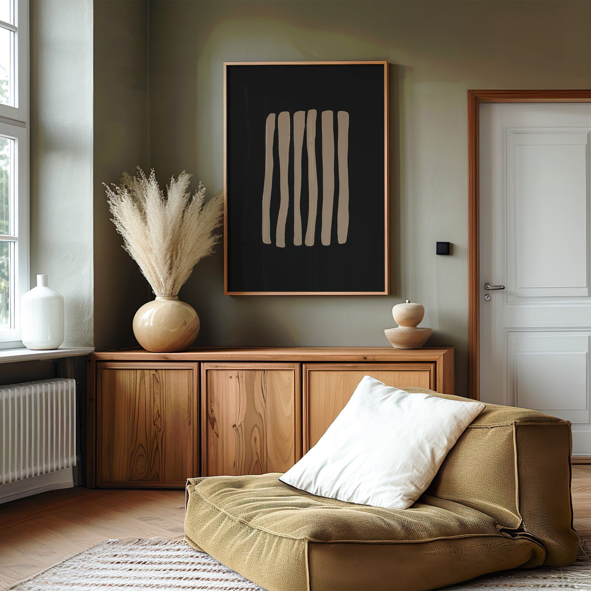 Taupe stripes on black background boho print in an oak frame on an olive green wall above a wood sideboard with pampas