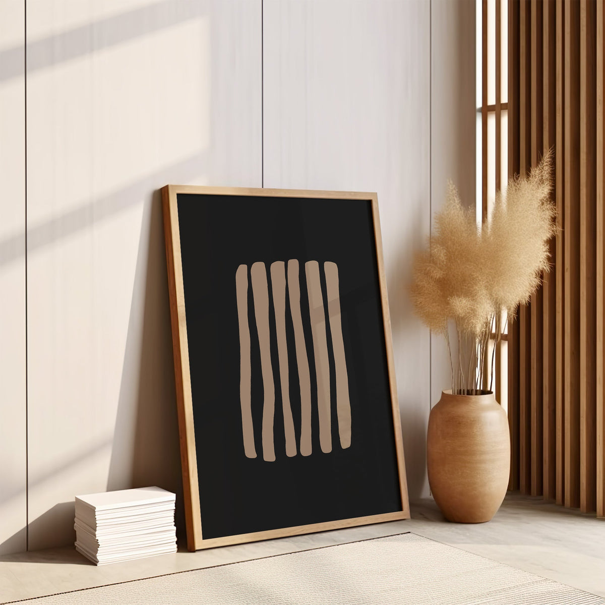 Taupe stripes on black background boho print in an oak frame leaning on the floor by pampas grass and a wood slat screen