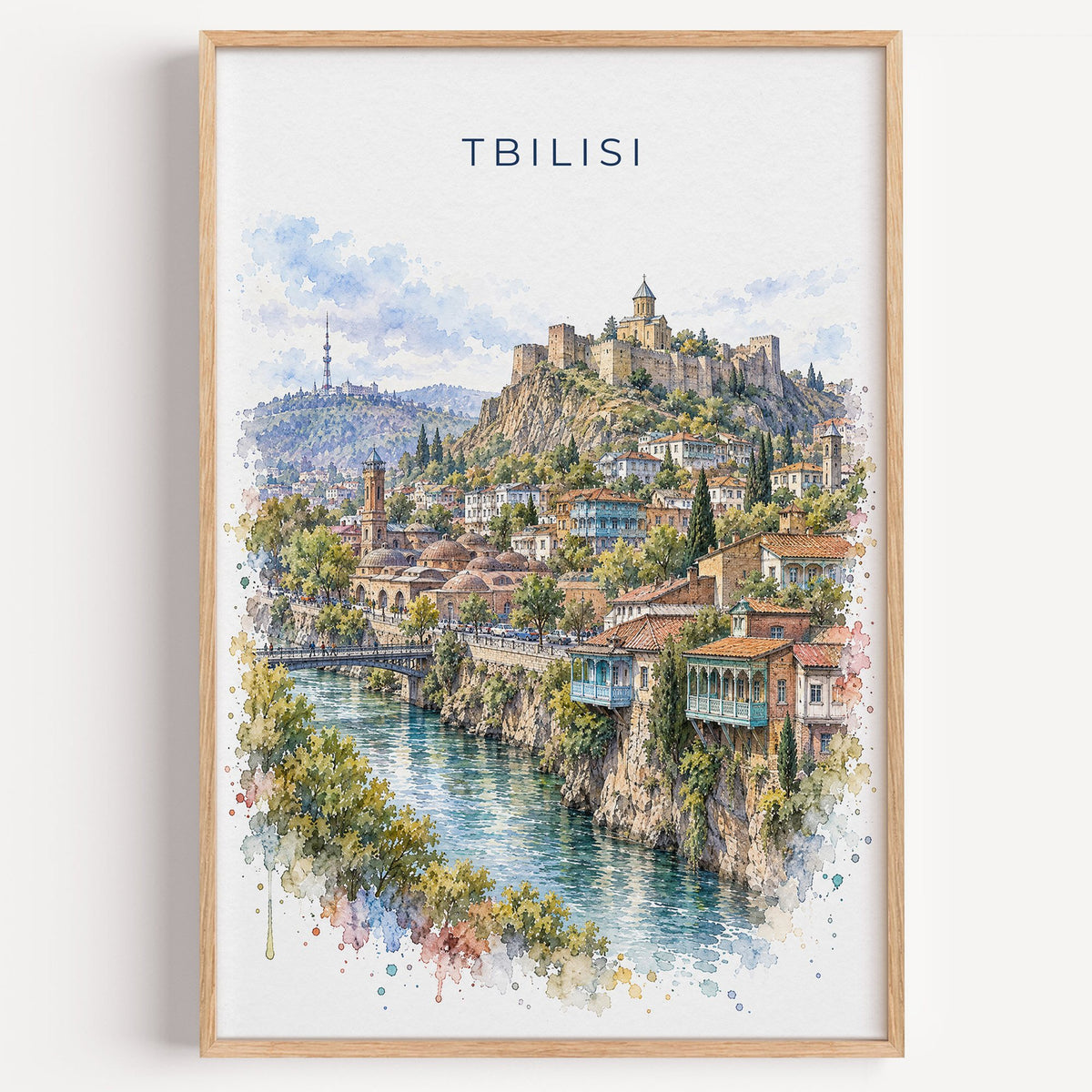 Tbilisi watercolor print in a light oak frame on a plain white wall
