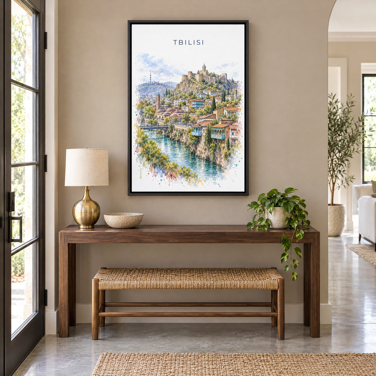 Tbilisi watercolor print as a black floater canvas above a walnut console and woven bench in an entryway